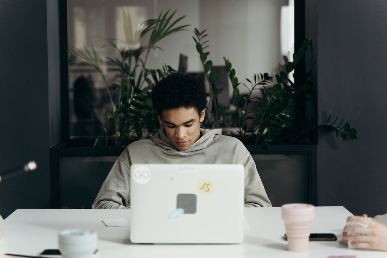 Focused young professional working on a laptop in a modern office environment.